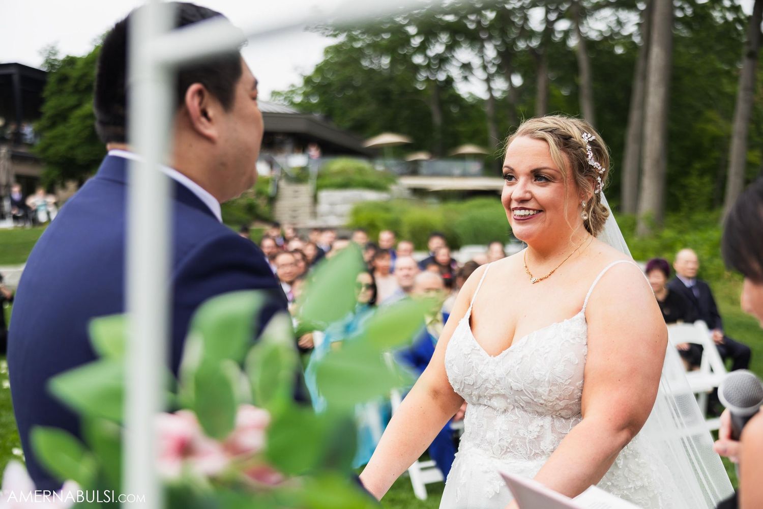 Outdoor wedding ceremony moment with decorative arch and golf carts visible in background.