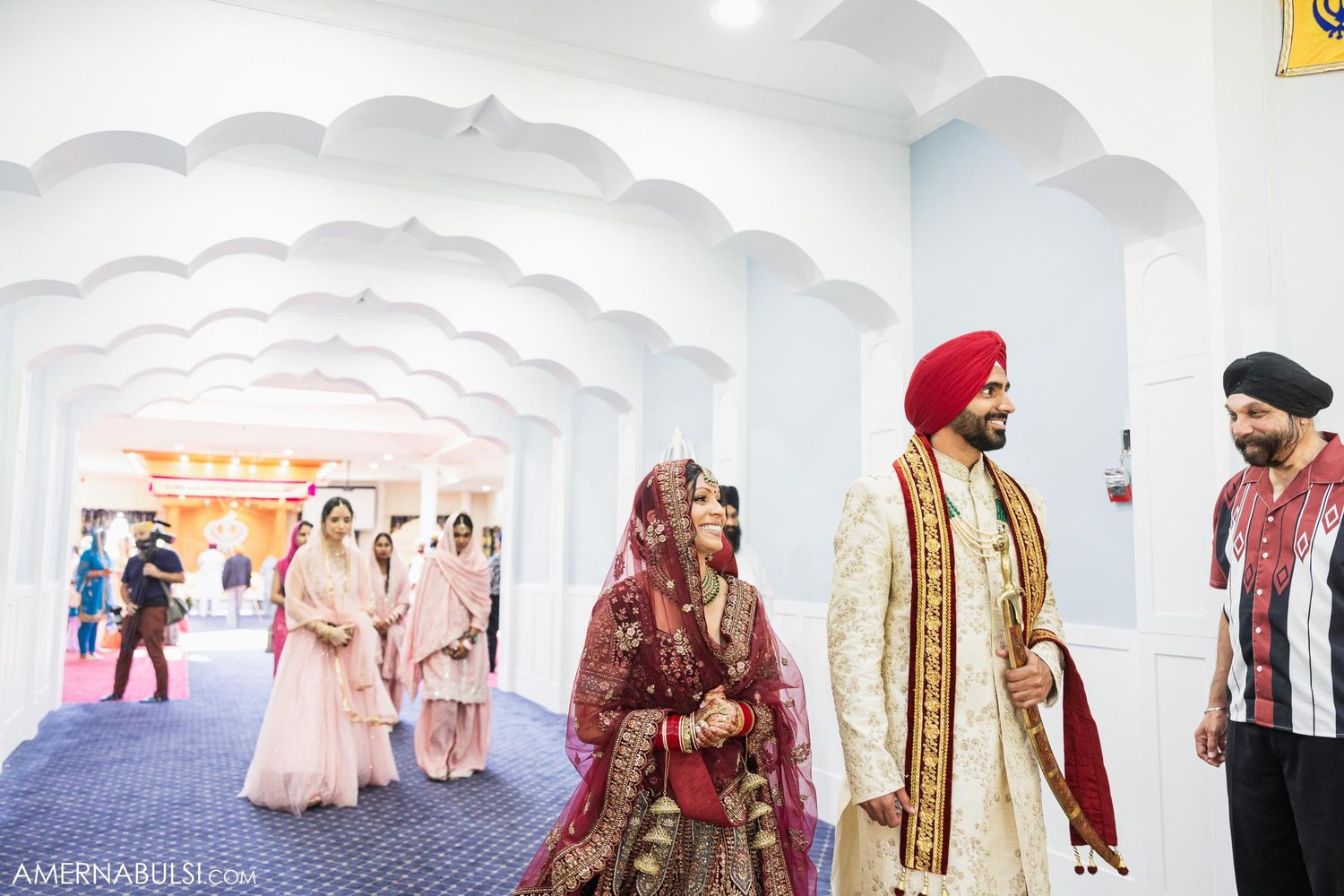 Wedding ceremony procession through ornate white hallway with arched ceiling.