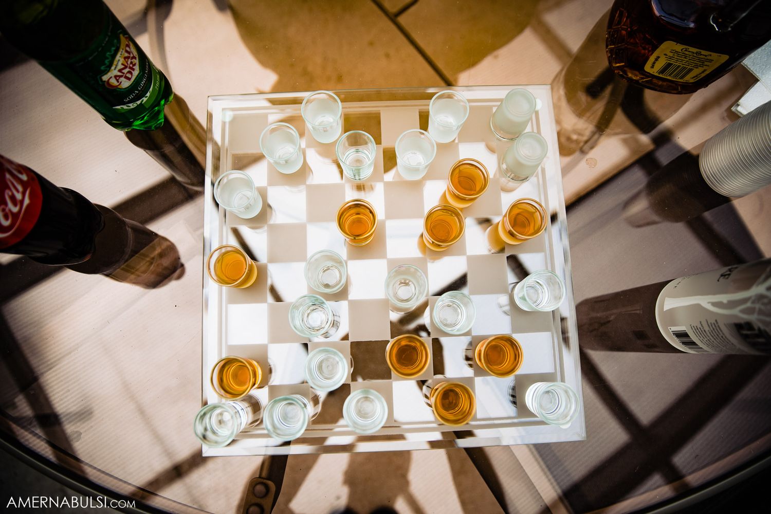 Multiple shot glasses filled with golden-colored spirits arranged neatly in white serving trays.