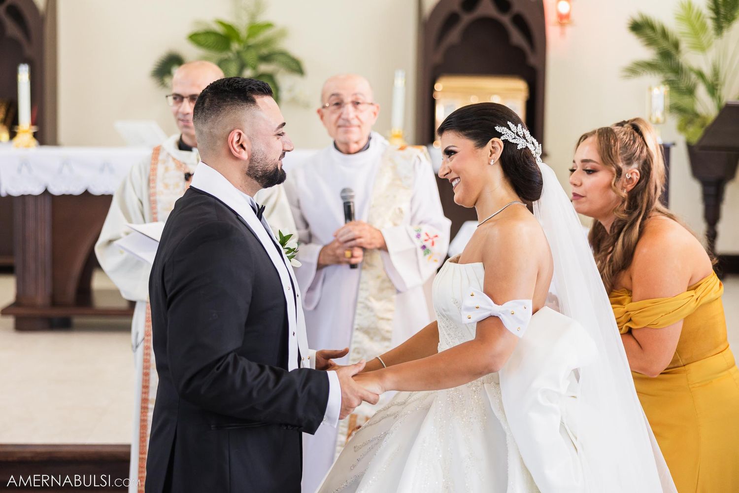Wedding ceremony in church with couple exchanging vows while bridesmaid in yellow dress looks on.