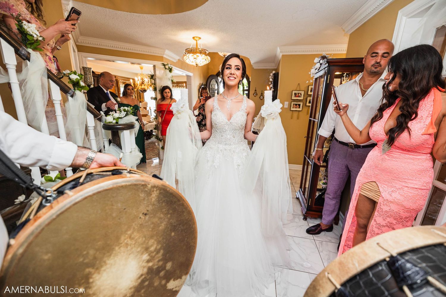 Wedding party dancing and celebrating around musicians playing drums at an indoor reception.