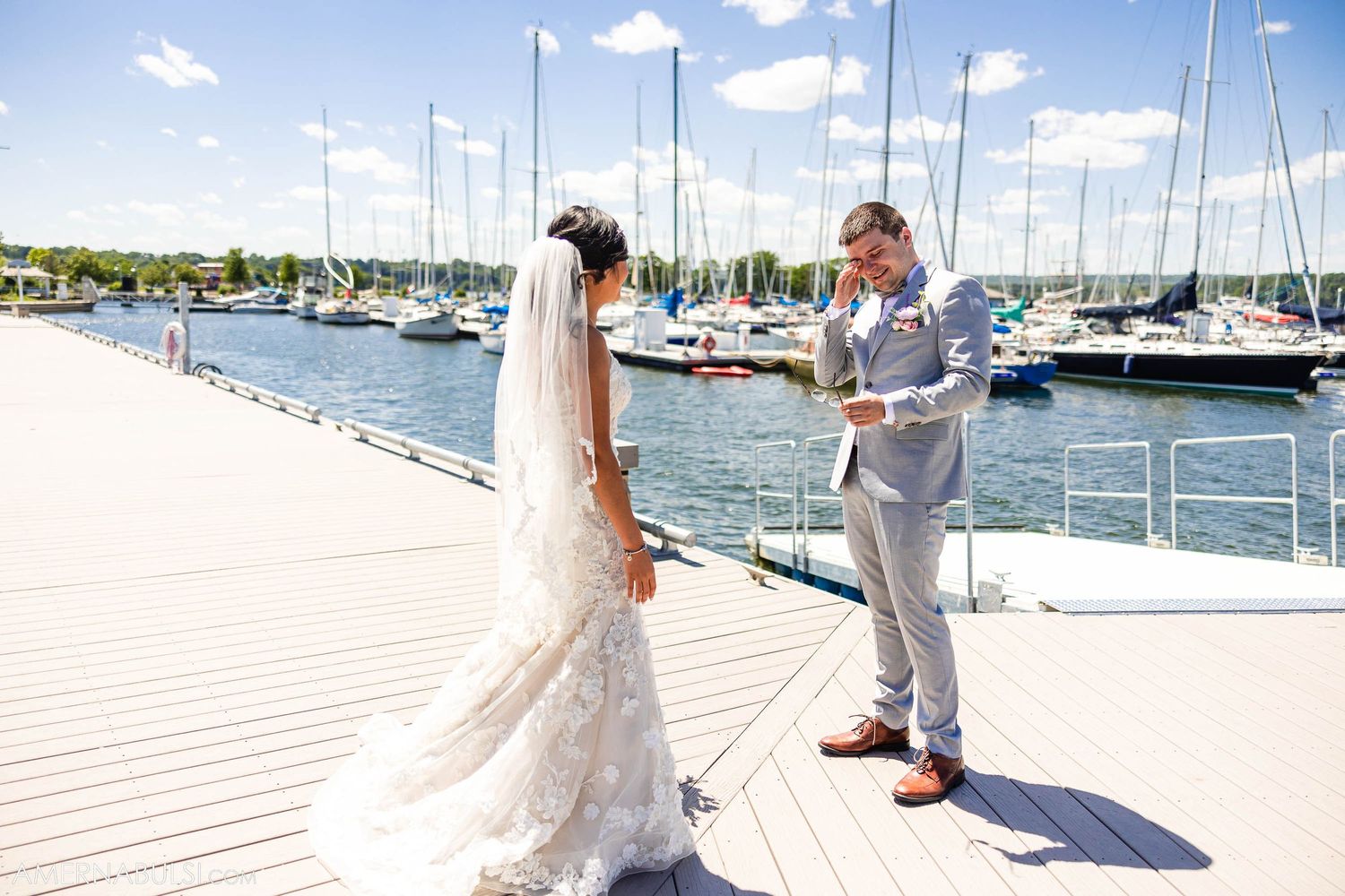Wedding couple exchanges vows on a marina dock with boats in the background.