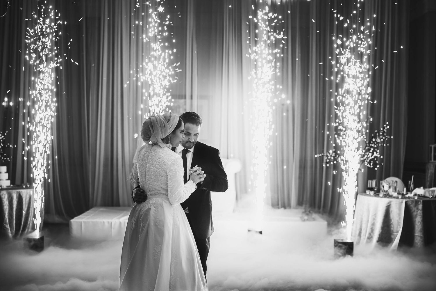 Black and white photo of couple's first dance with sparkler fountains creating a magical backdrop.