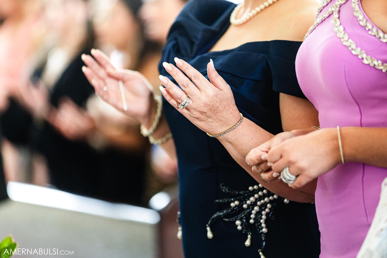 Wedding guests in formal attire applaud during ceremony in church.