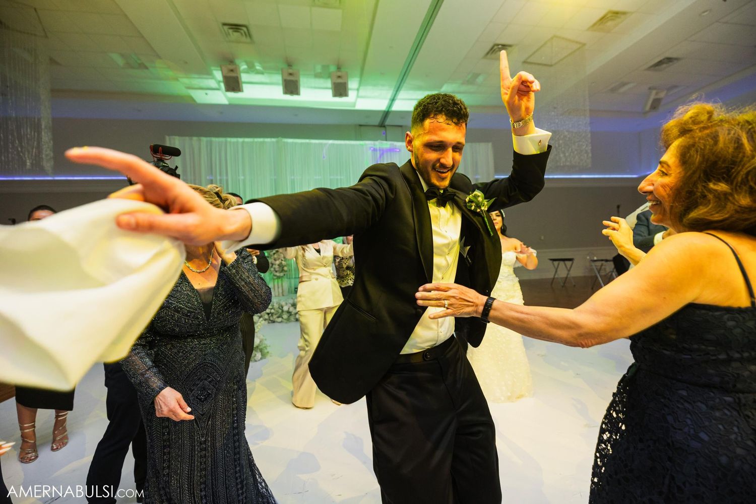 Wedding guests dance enthusiastically during a lively reception celebration.