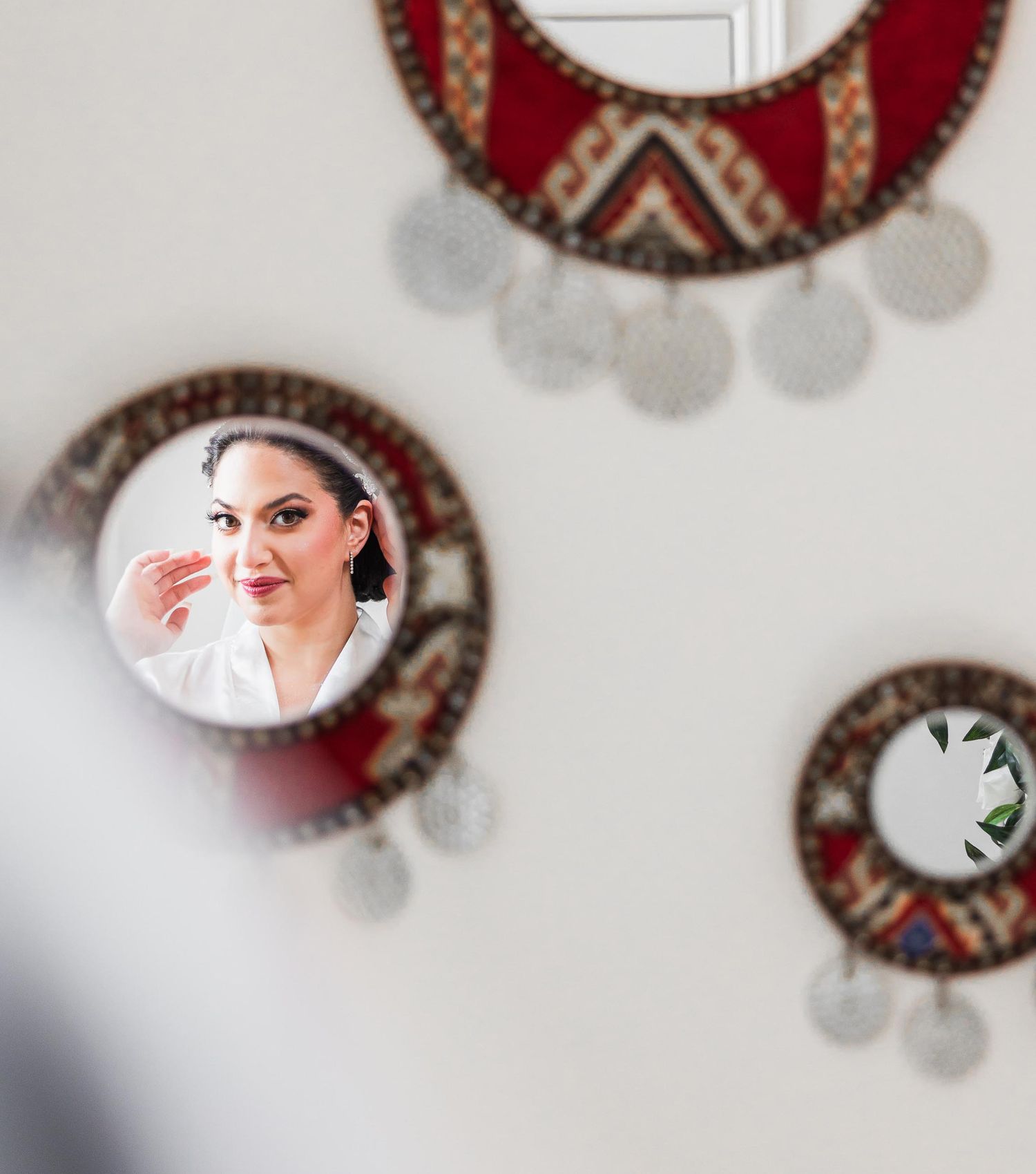Creative reflection of bridal preparation in decorative circular mirrors with red accents.