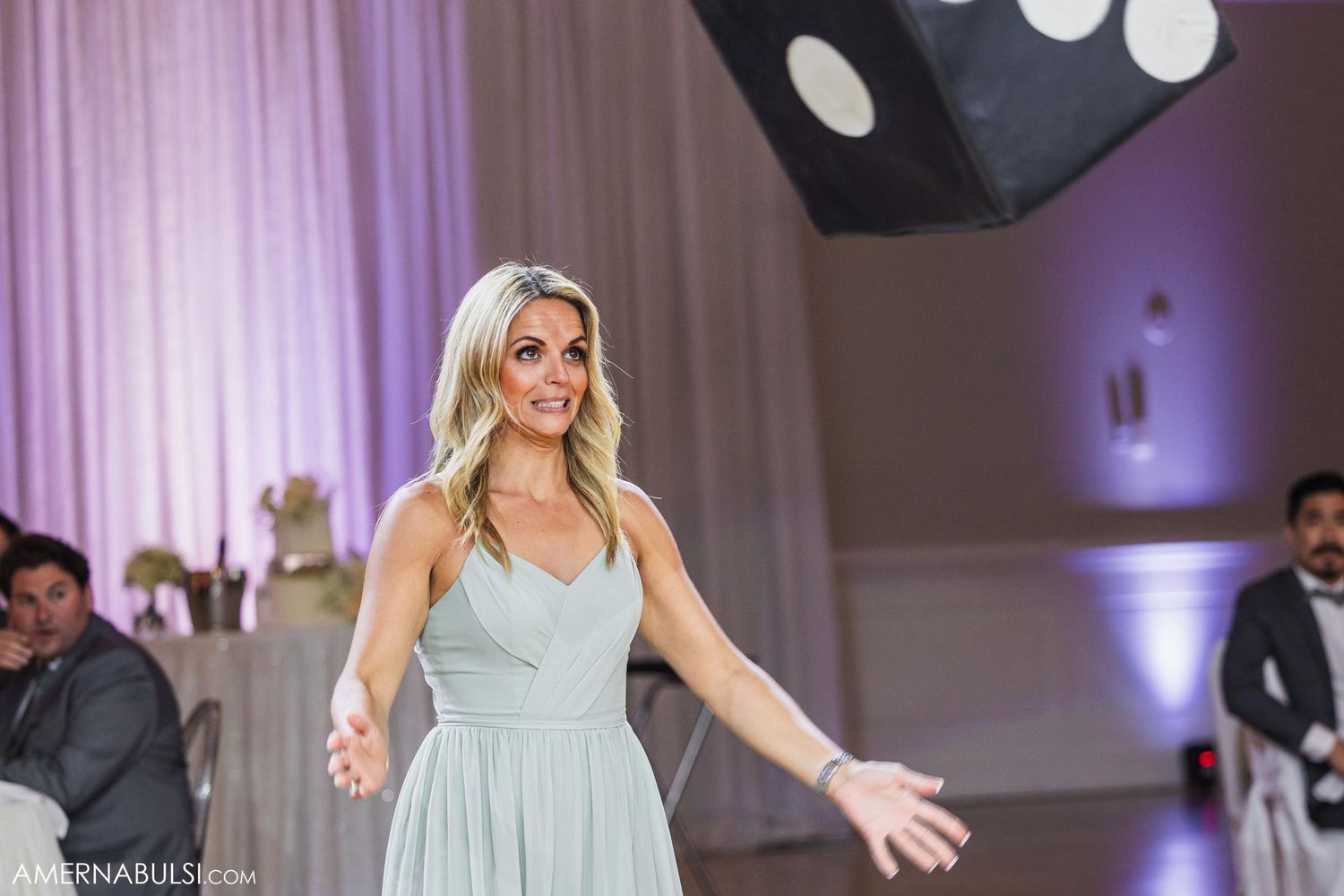 Woman in pale blue dress dancing joyfully at formal event.