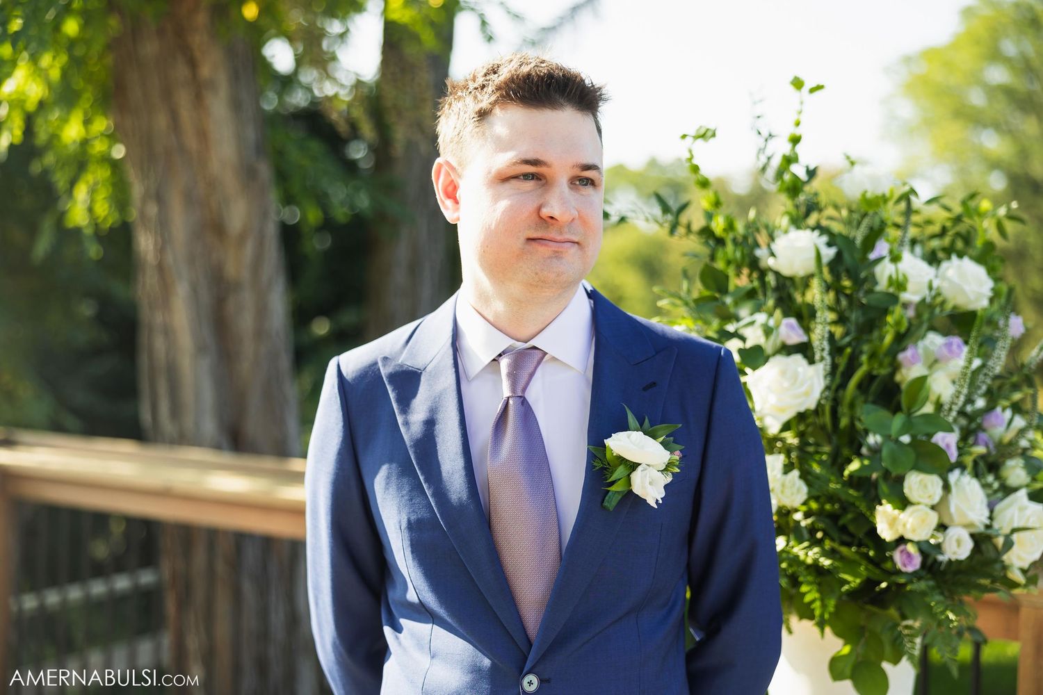 Formal portrait in a garden setting with white floral arrangements and greenery.