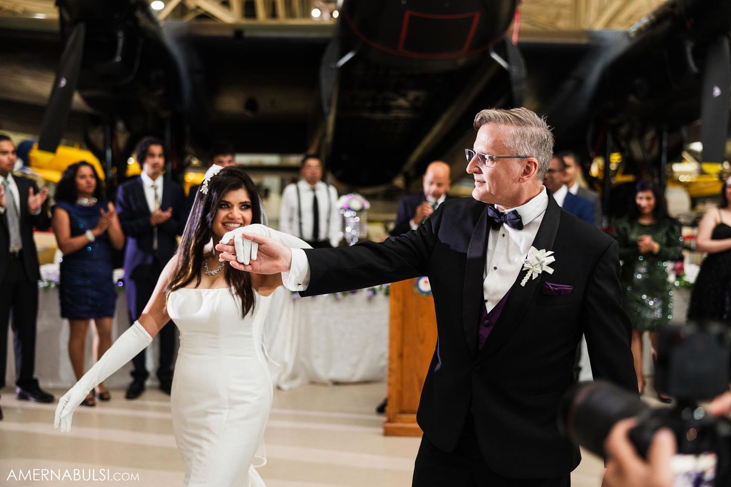 Wedding couple performs elegant dance moves in an aircraft hangar.