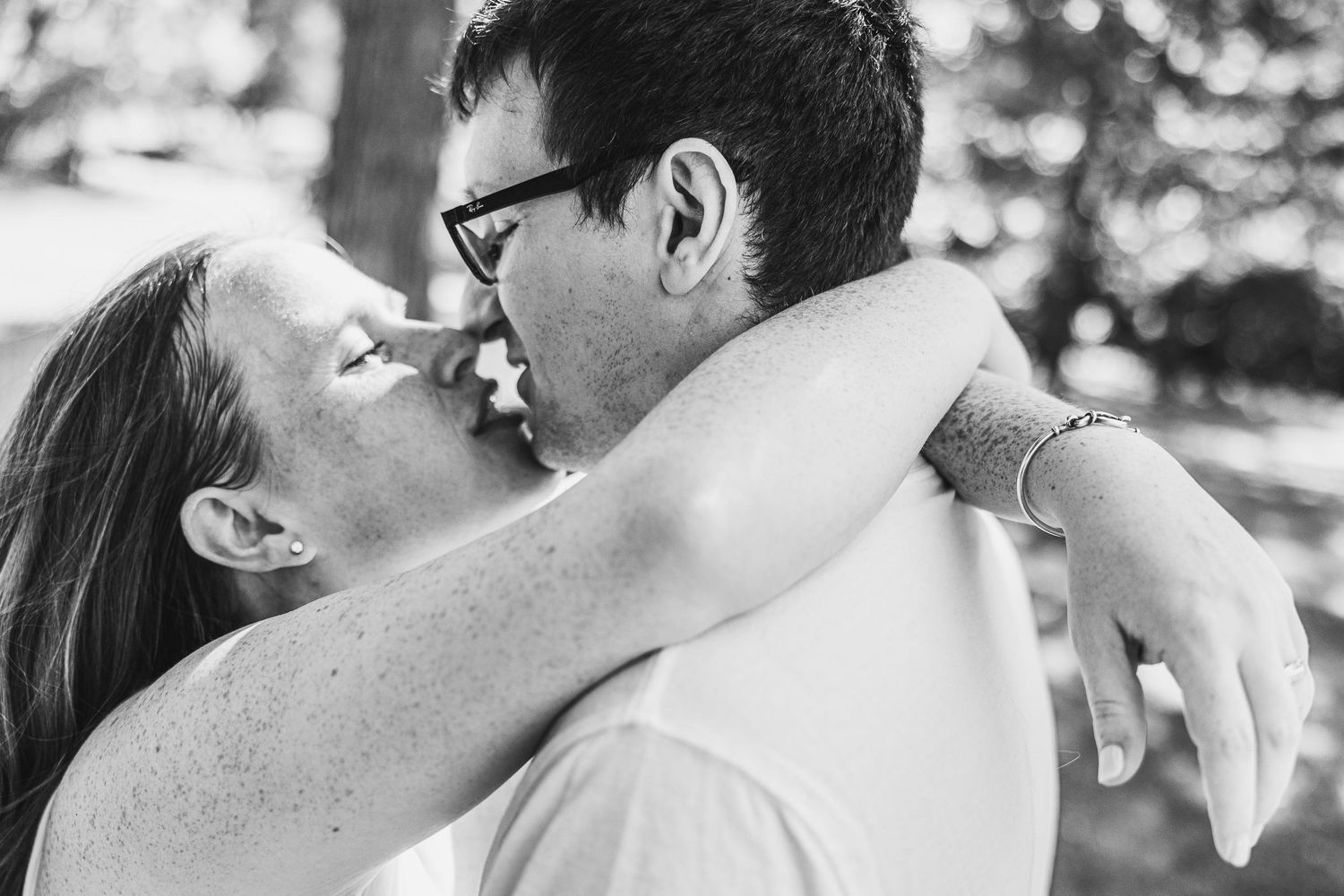 Romantic embrace captured in black and white outdoor setting.