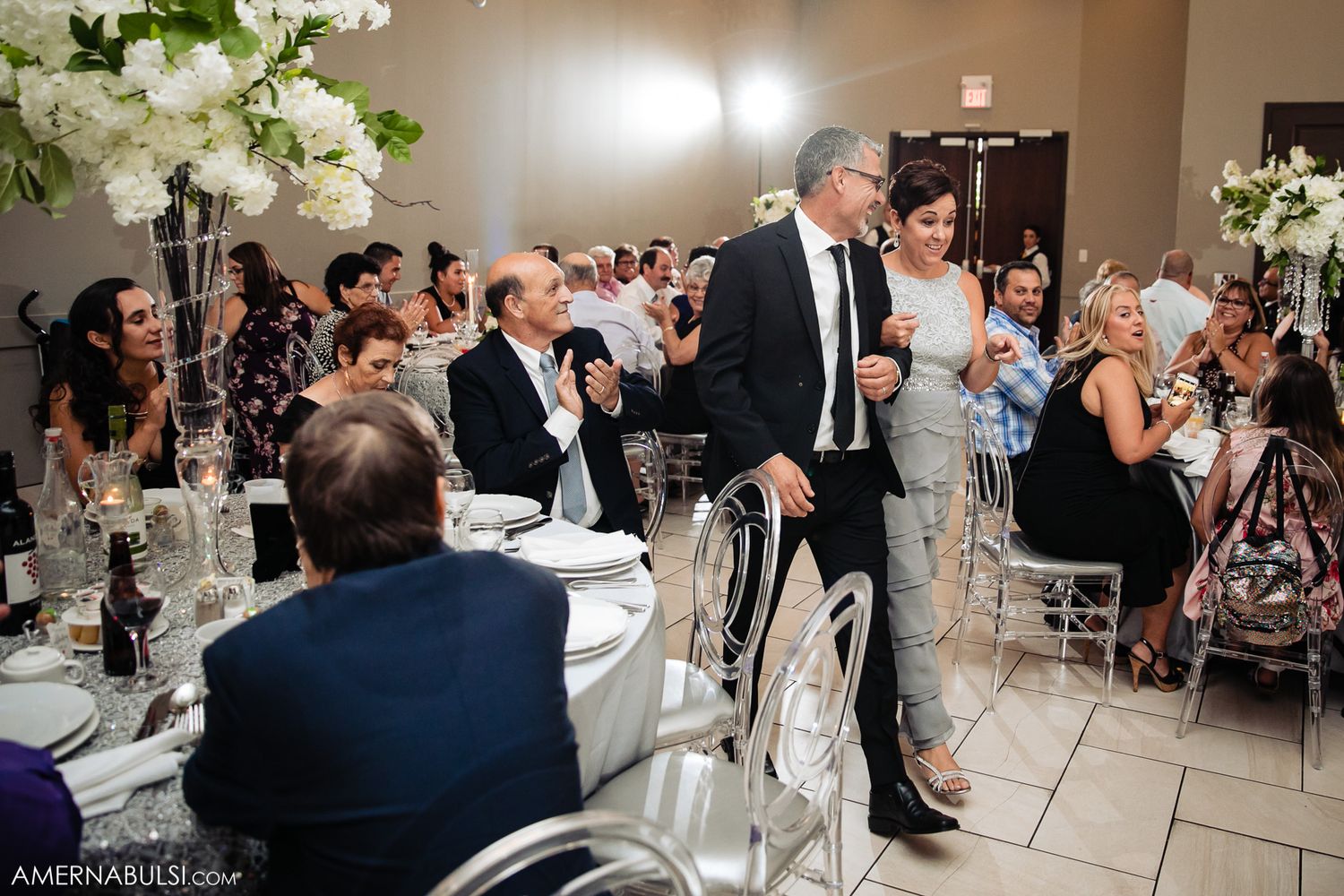 Wedding reception venue decorated with white floral arrangements and elegant table settings.