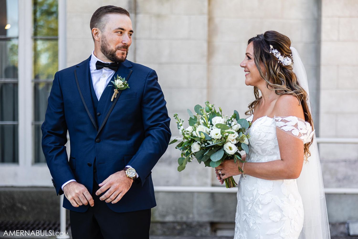 Elegant couple shares a first look moment outside a grand building entrance.