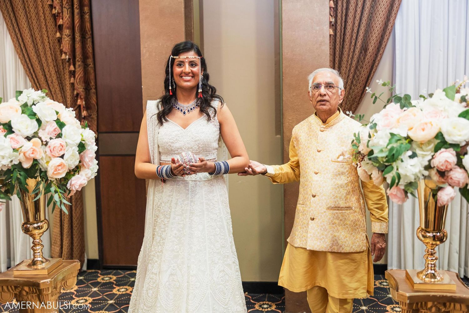 Wedding celebration with elegant floral arrangements and gold decor in formal venue setting.