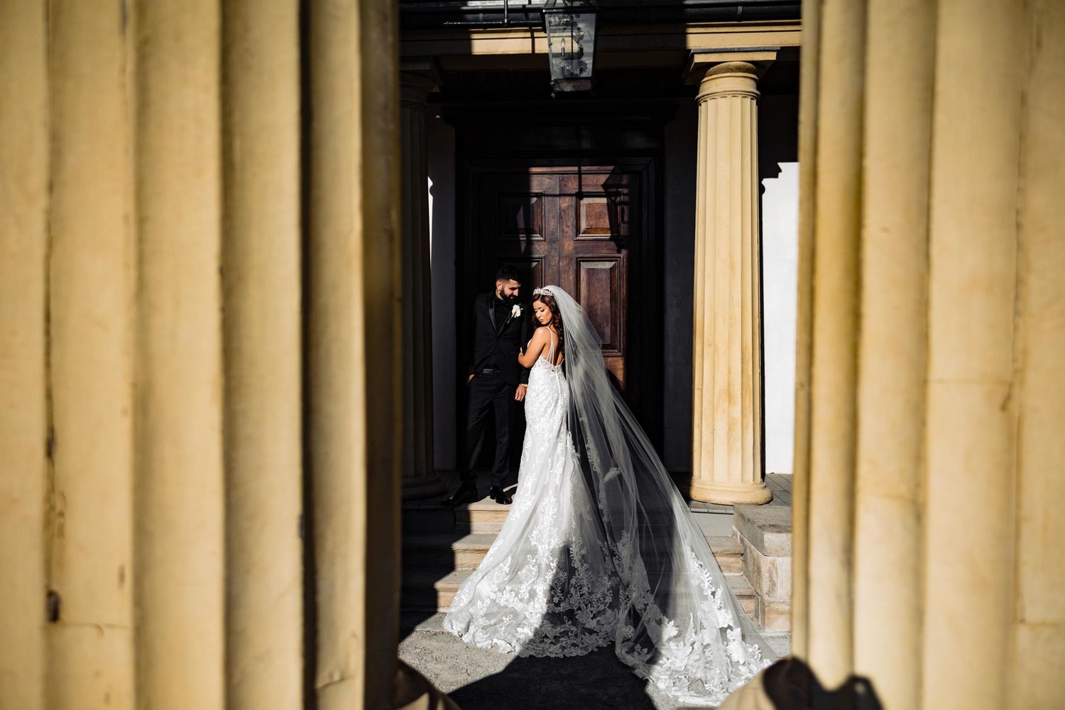 Elegant bridal portrait with flowing veil between classic stone columns.