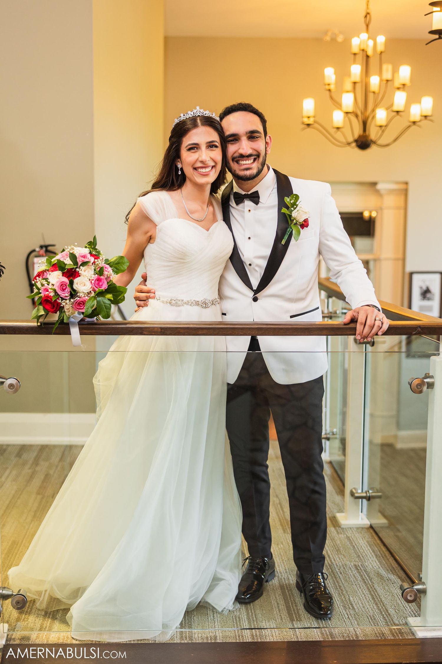 The newlyweds pose elegantly by a railing in their wedding attire.
