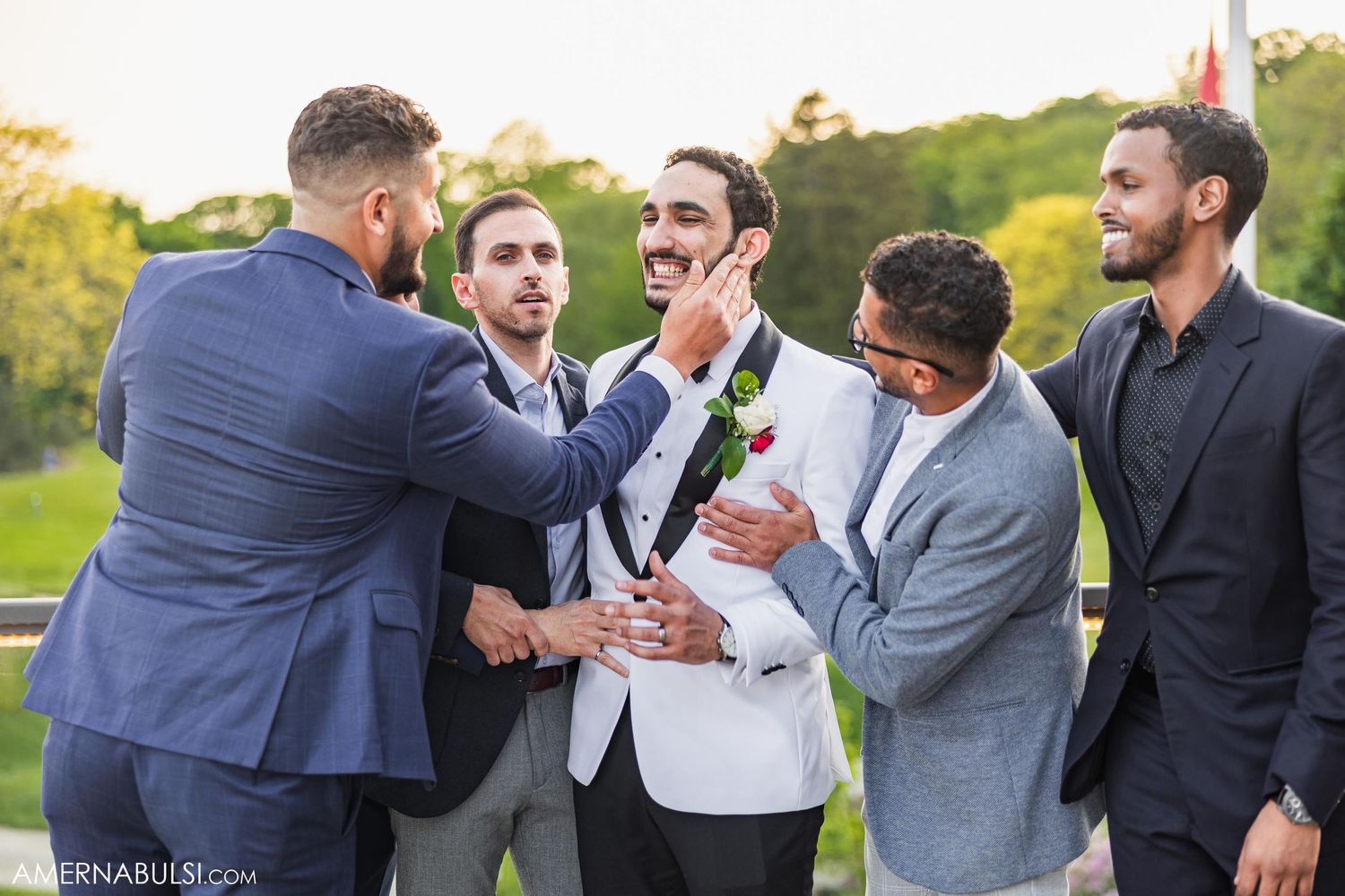 Groomsmen sharing a playful moment outdoors during wedding celebrations.