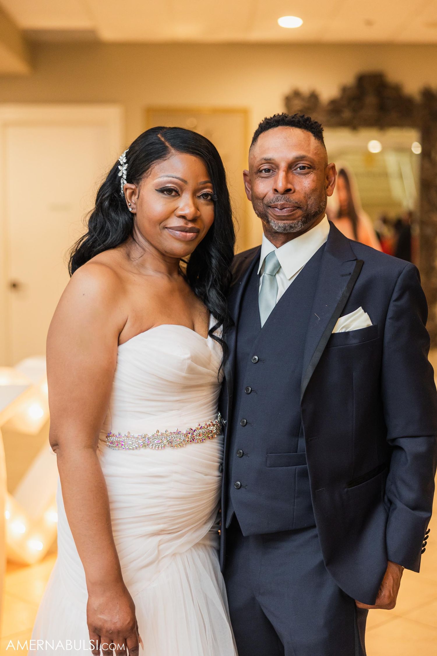A couple dressed in elegant wedding attire pose for a formal portrait.