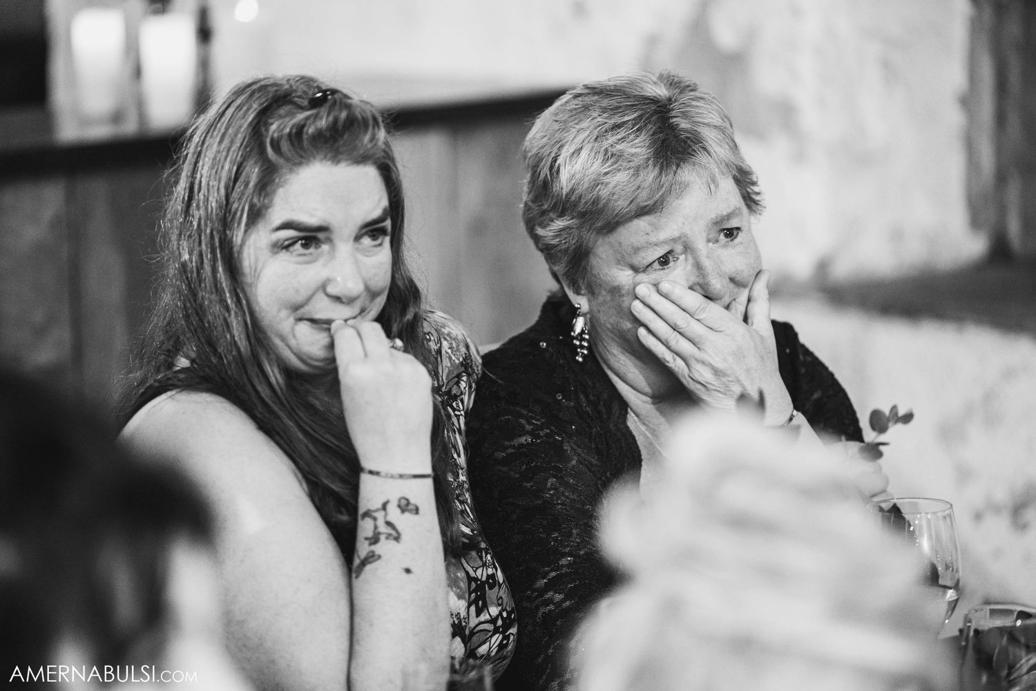 Two guests react emotionally during speeches at a wedding reception.