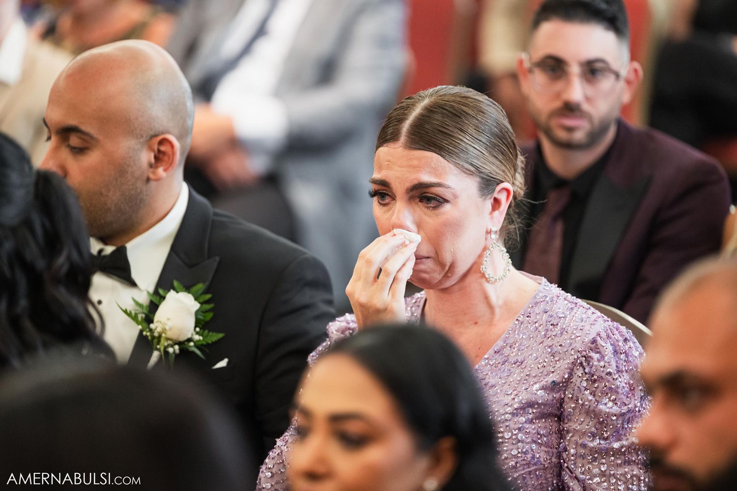 An emotional wedding guest dabs tears with a tissue during the ceremony.