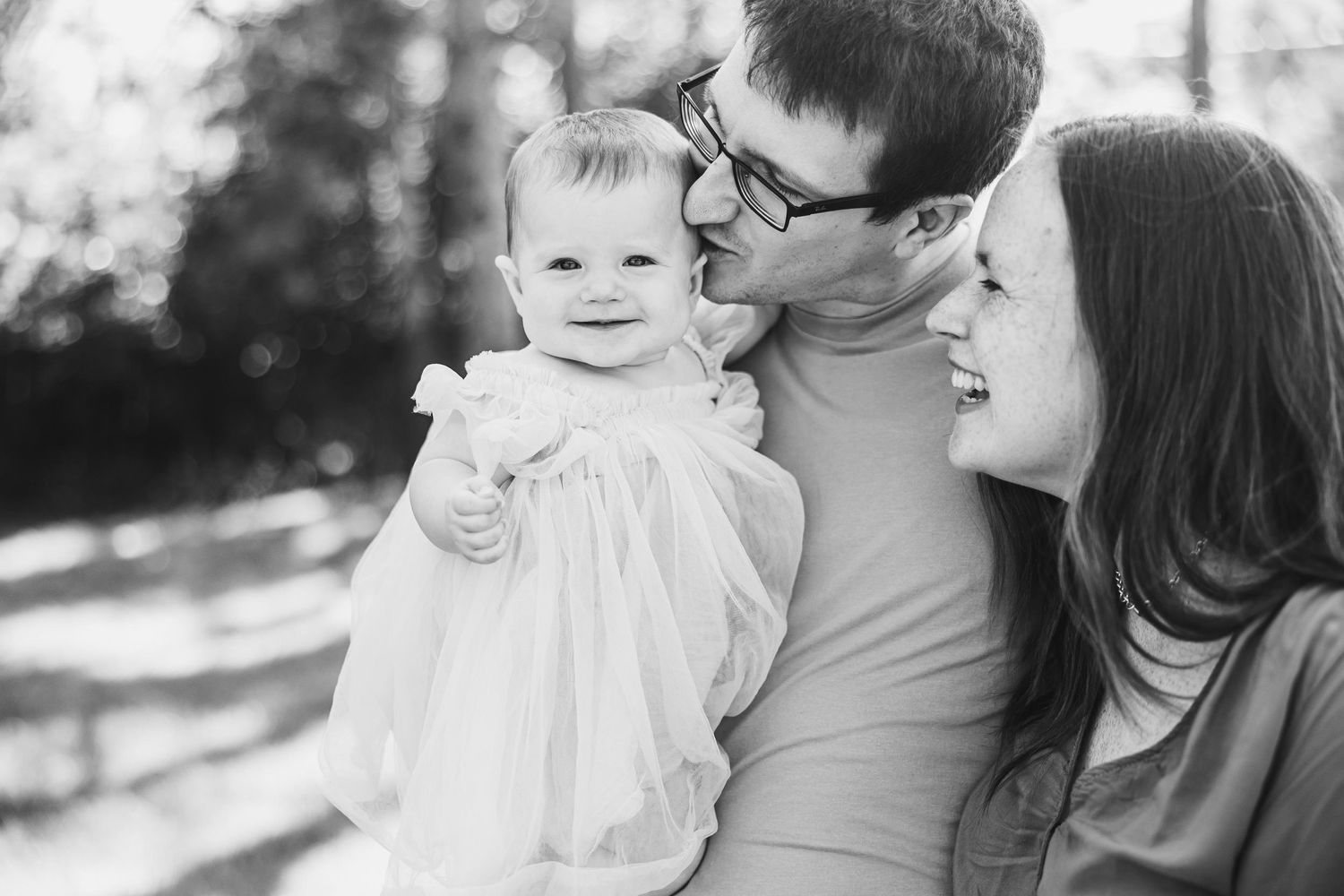 Black and white portrait of family sharing tender moment outdoors.