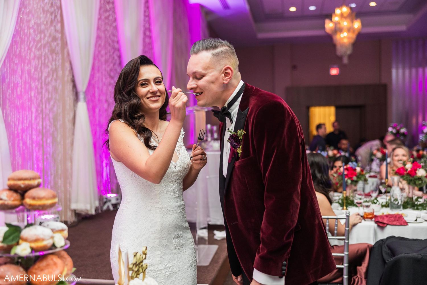 Newlyweds share a sweet moment at their reception table with pink decor.