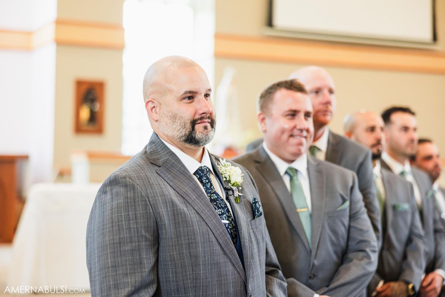 Wedding party members stand at the altar in formal attire during the ceremony.