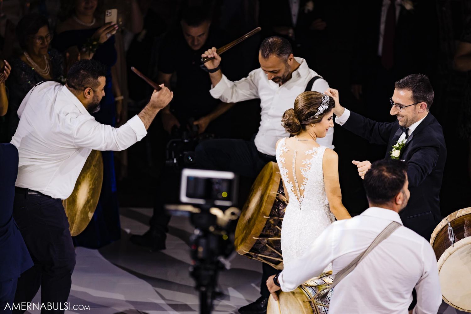 Musicians with large drums perform while couples dance during a wedding celebration.