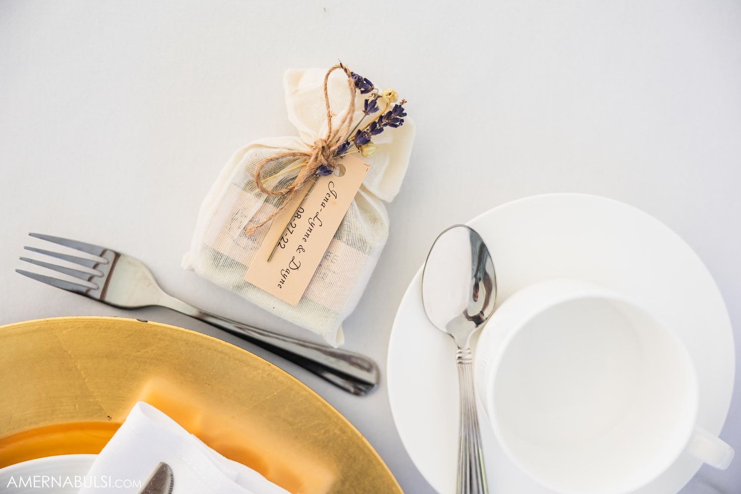 Place setting with gold charger plate and favor bag at wedding reception.