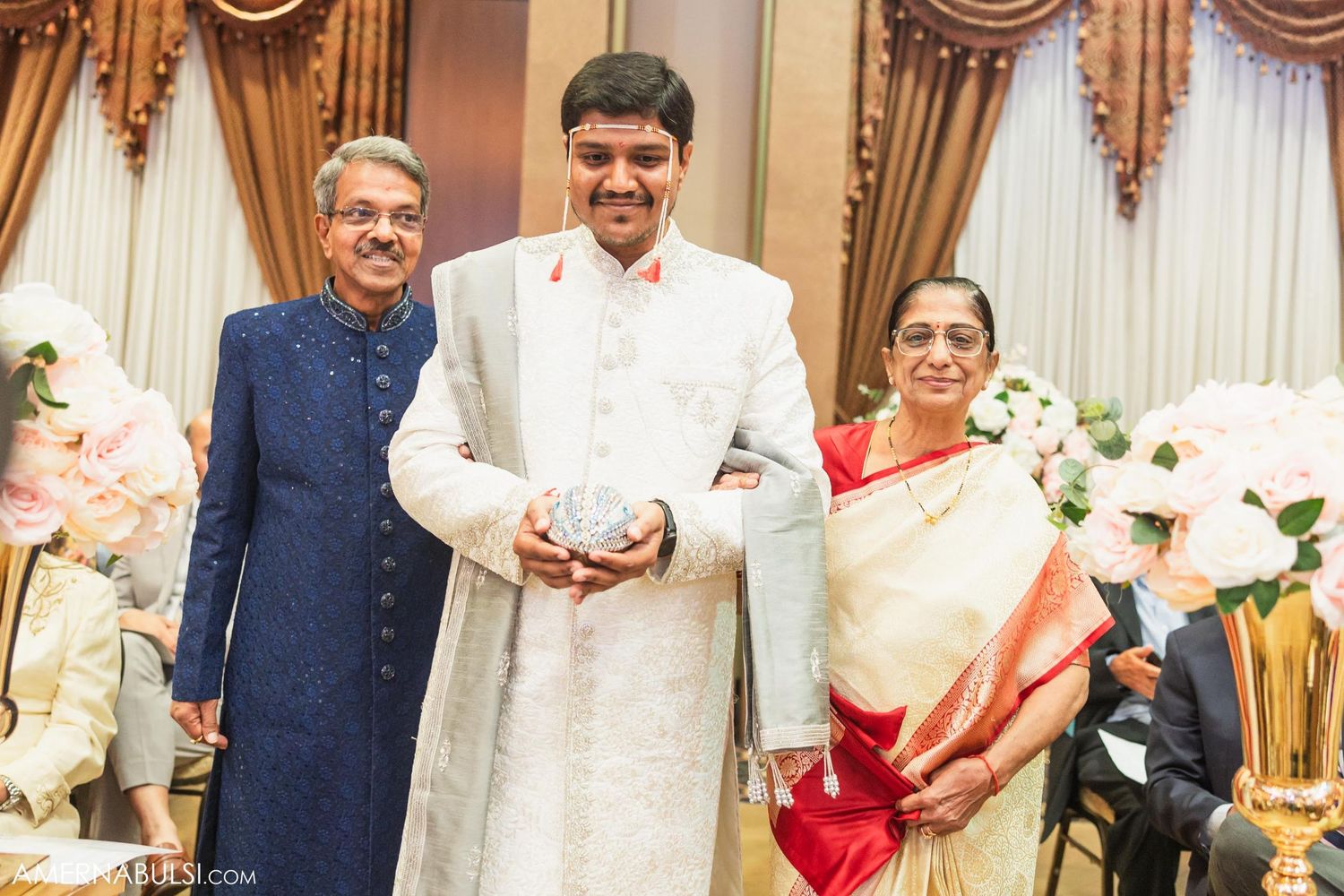 Family group poses together in traditional Indian formal wear during a wedding celebration.