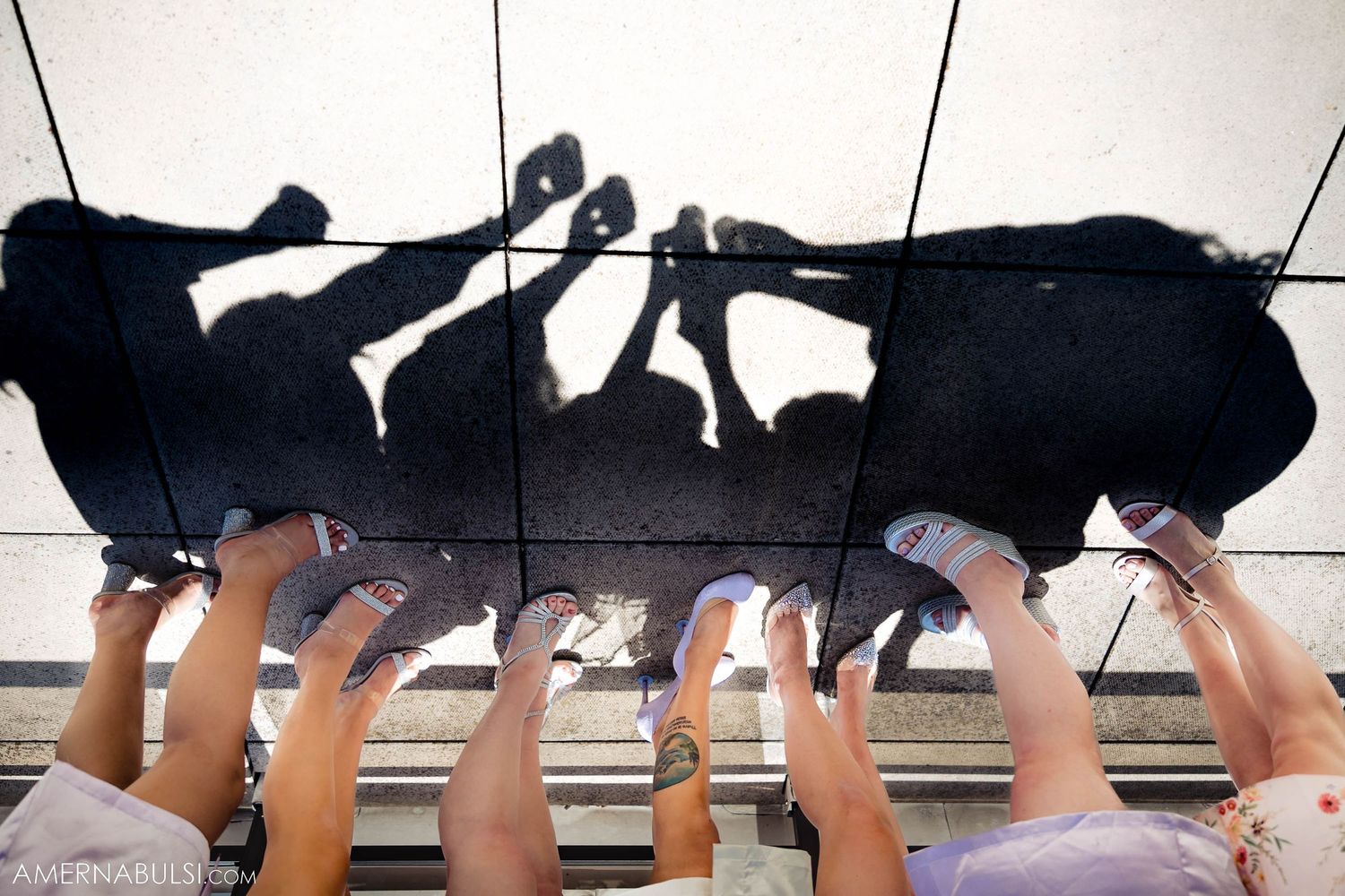 Creative shadow silhouette of wedding party legs against white floor.