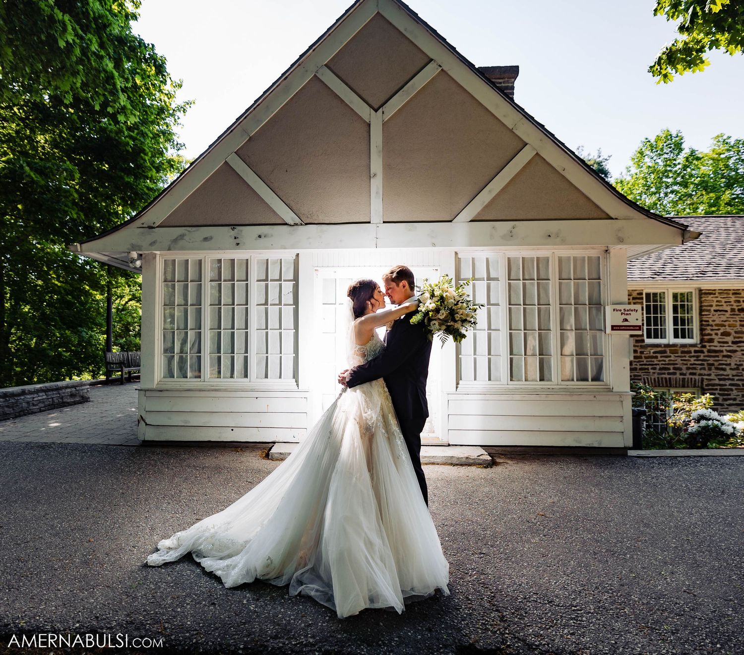 Romantic dance pose in front of white chapel building on wedding day.