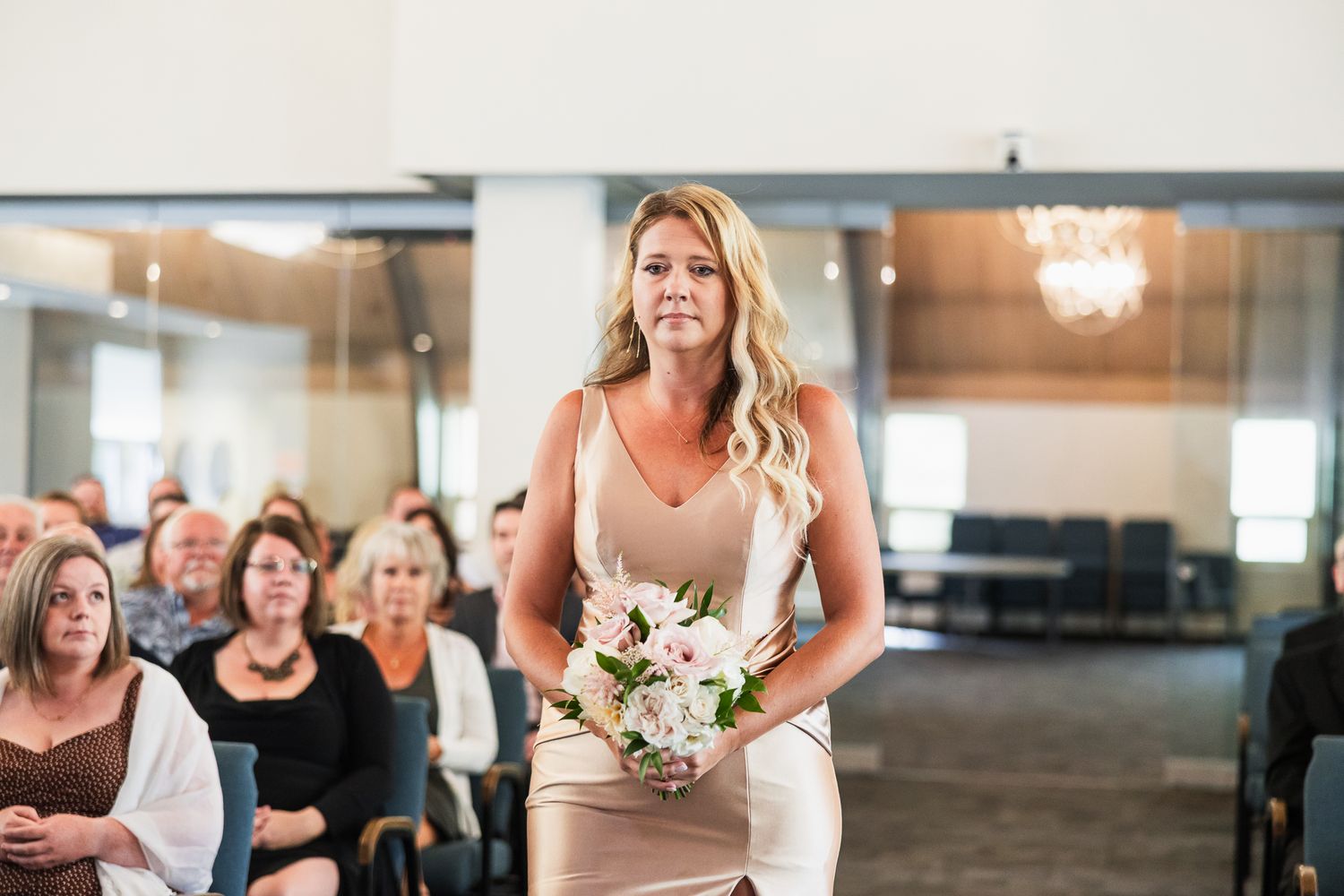 Wedding ceremony taking place in a bright, modern venue with guests looking on.