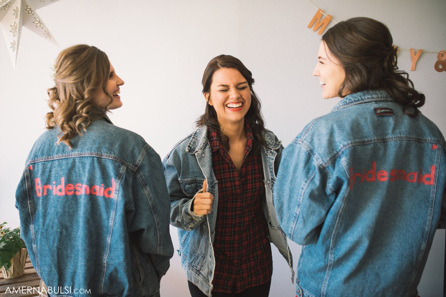 Row of women wearing matching denim jackets with embroidered text on the back.