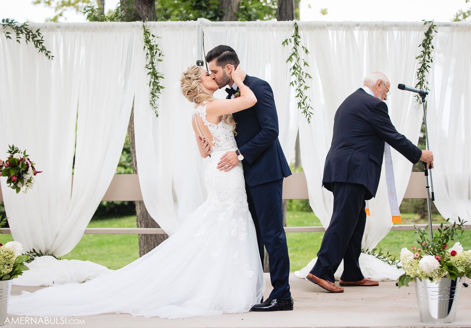 Elegant outdoor wedding ceremony setup with flowing white curtains and floral decorations.