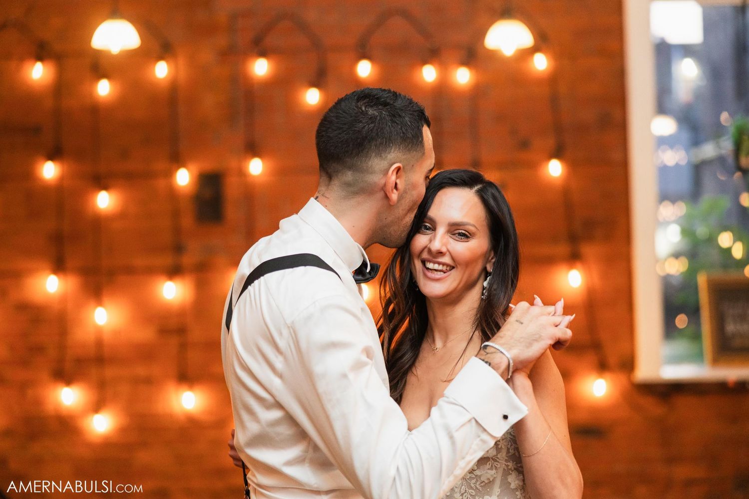 Couple sharing a joyful moment while dancing under string lights.
