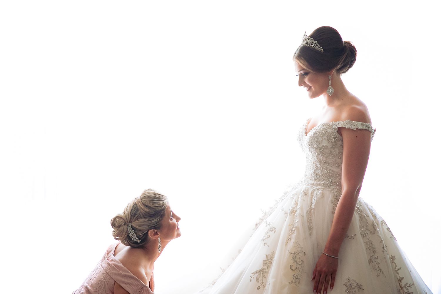 Delicate details of a white lace wedding dress silhouetted against natural light.