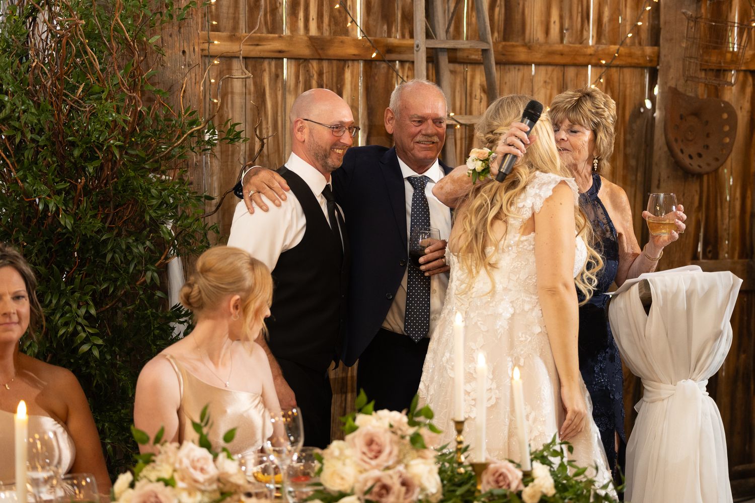 Wedding reception tables decorated with lush greenery and soft lighting in a charming barn setting.