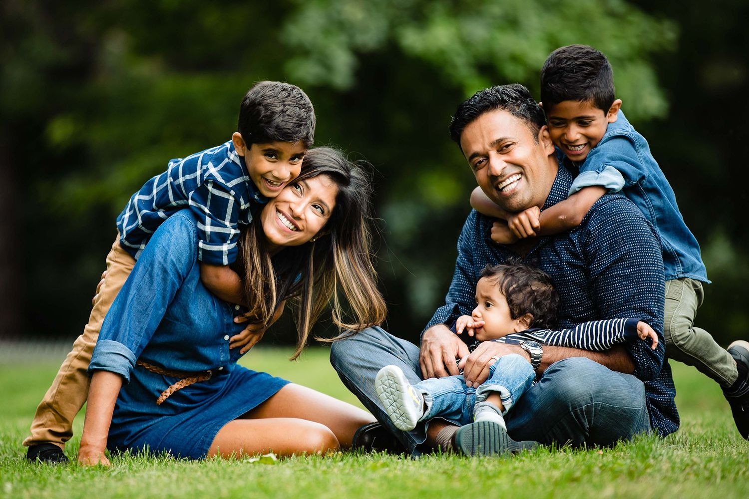 A joyful family relaxes together on green grass during an outdoor photo session.