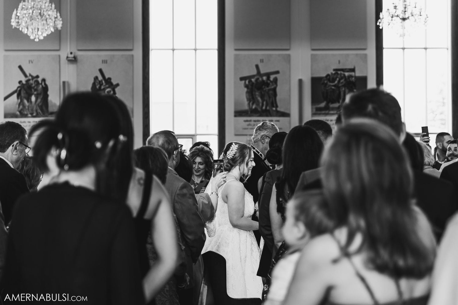 Black and white photo of a wedding reception with guests gathering in an elegant hall.