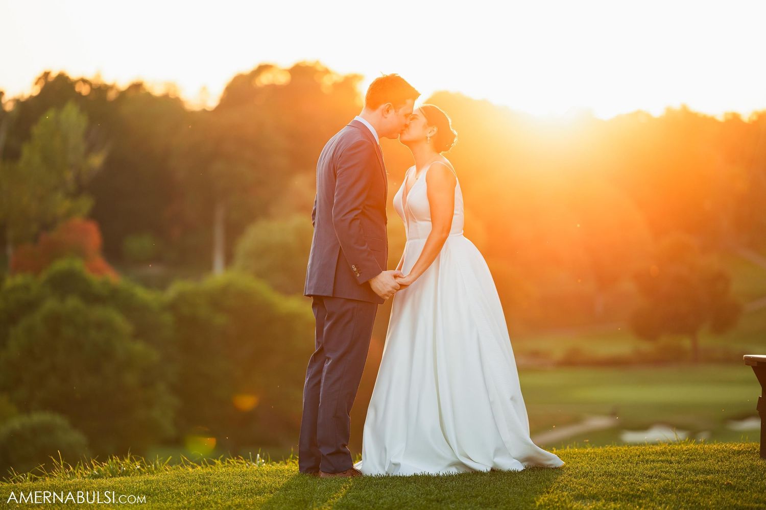 A romantic sunset wedding portrait shows a couple silhouetted against the glowing sky on a hillside.