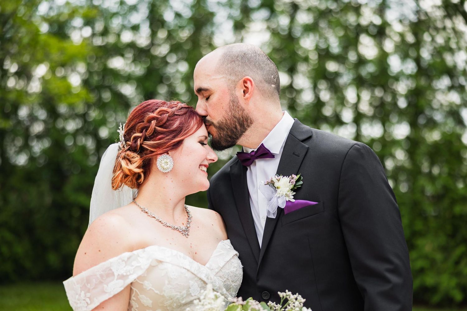 Romantic wedding moment captured outdoors with elegant white dress and formal attire.