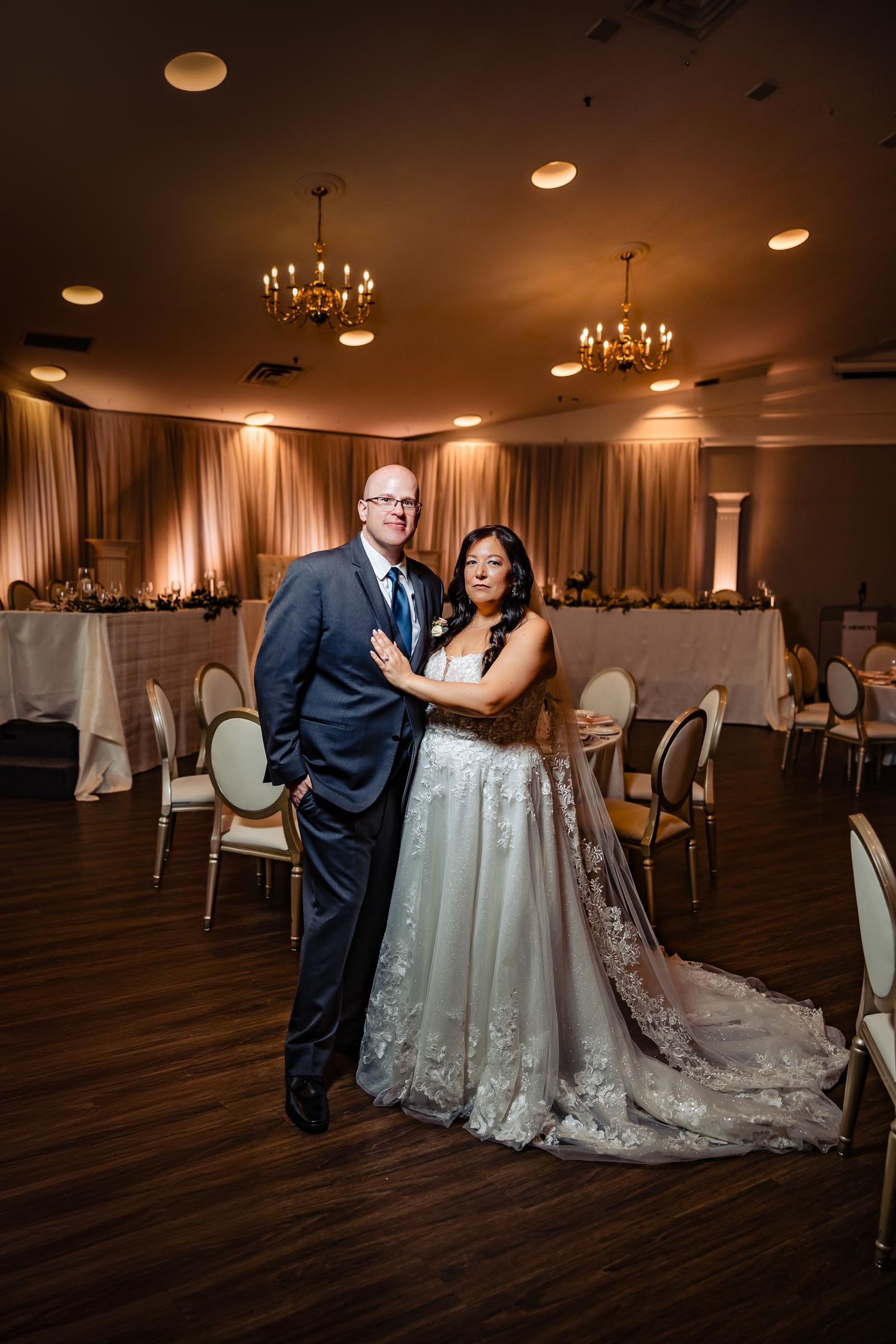 Wedding reception venue with soft lighting, chandeliers and draped fabric walls.