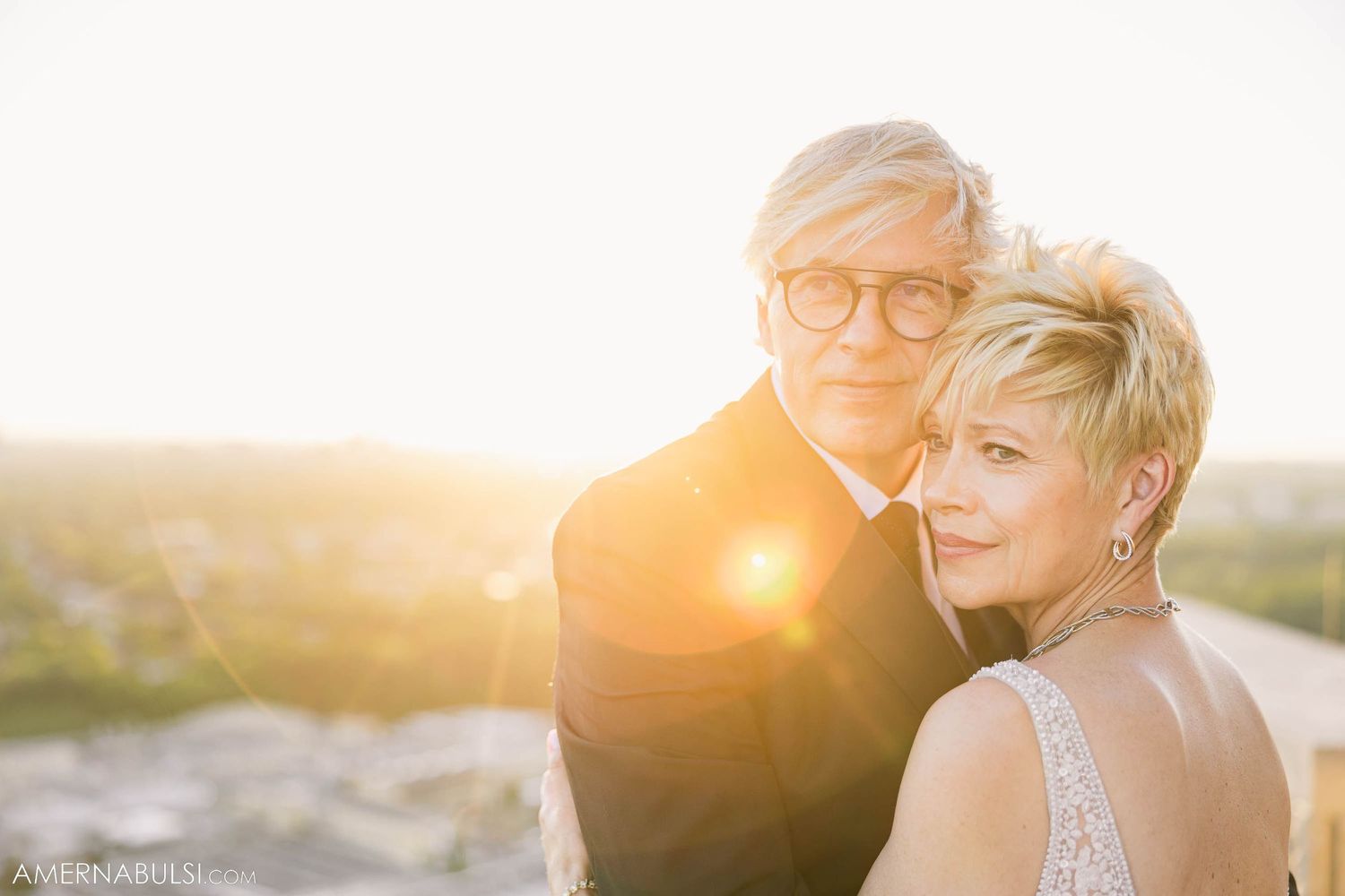 A couple shares a close embrace during golden hour on their wedding day.