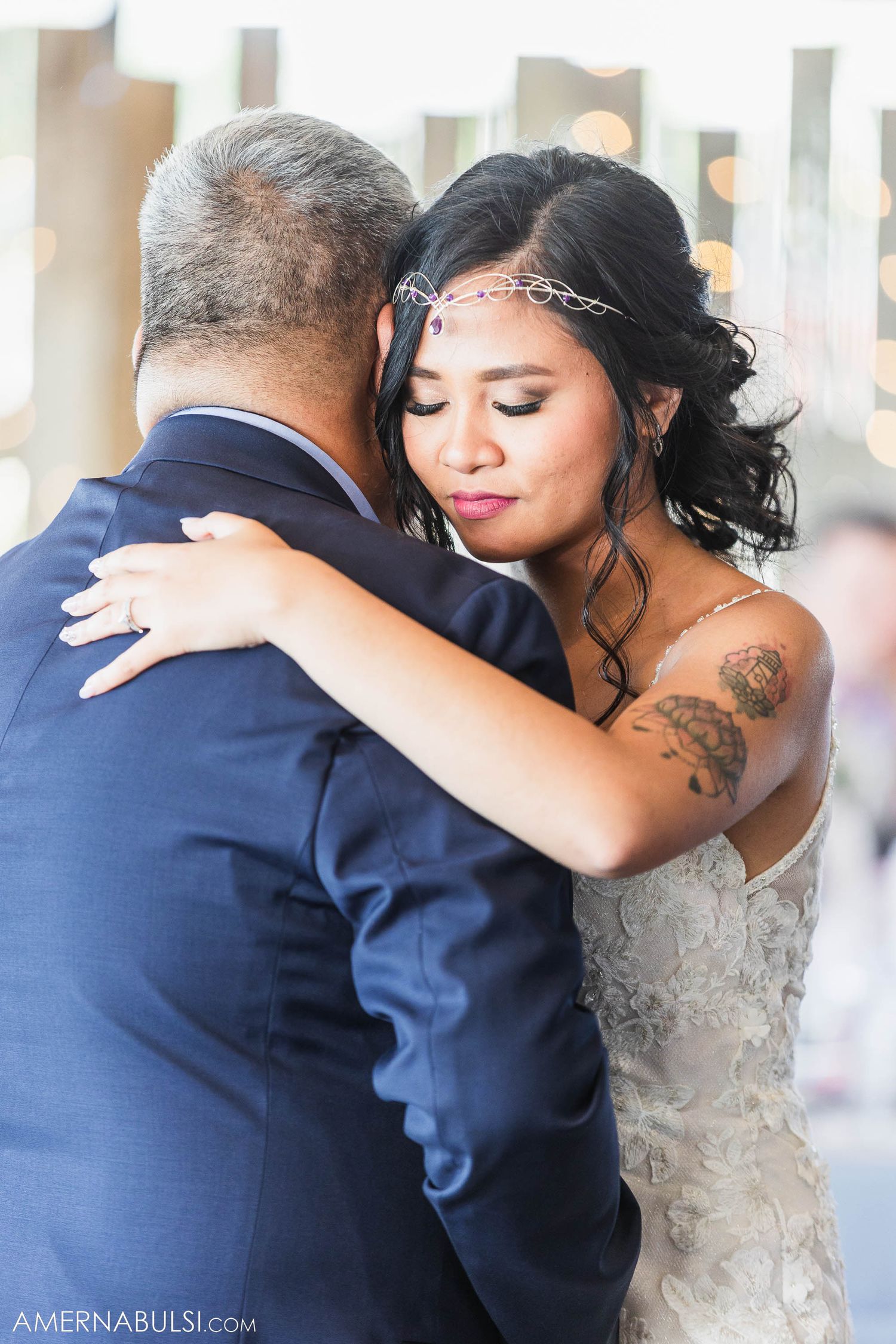 Couple embraces during an intimate wedding dance while guests look on.