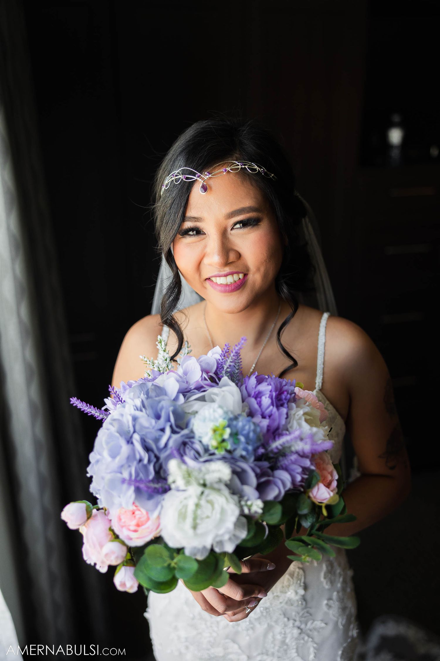 A bouquet of purple and pink flowers with roses and hydrangeas against dark background.