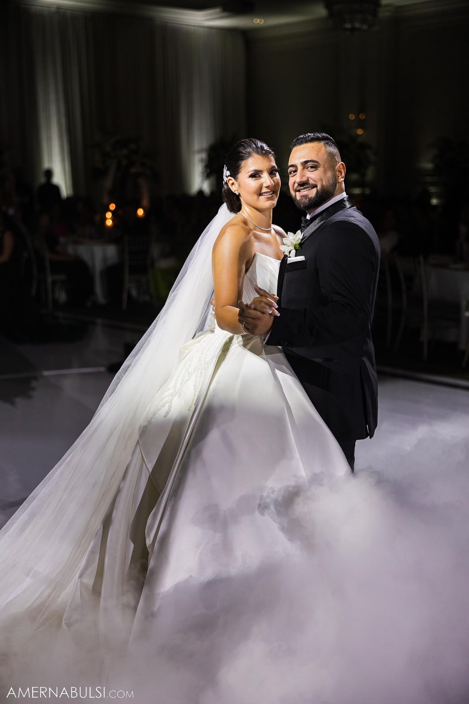 Newlyweds embrace during romantic dance surrounded by atmospheric fog effects.