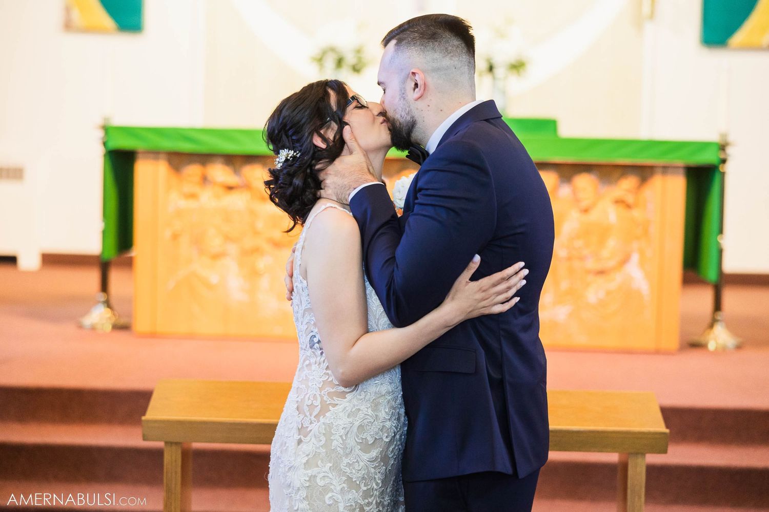 Romantic kiss between newlyweds at altar during church ceremony.