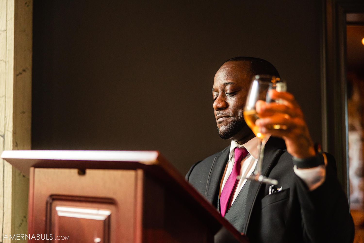 A person in formal attire raising a toast at a wedding reception.
