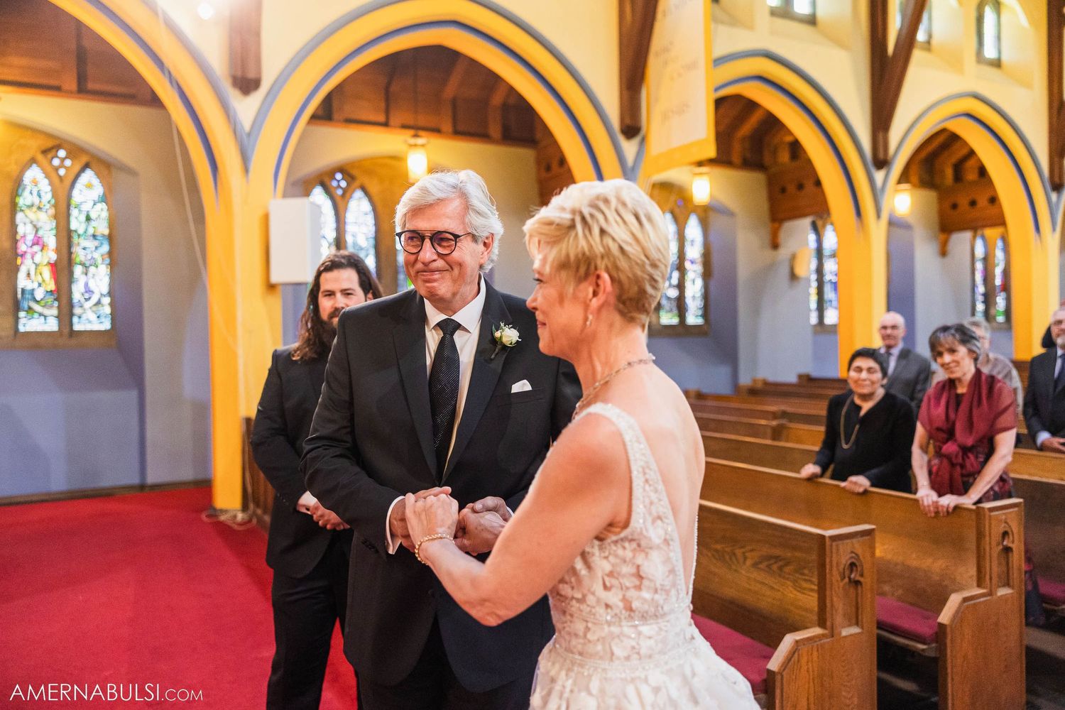Wedding ceremony in traditional church with golden arches and stained glass windows.