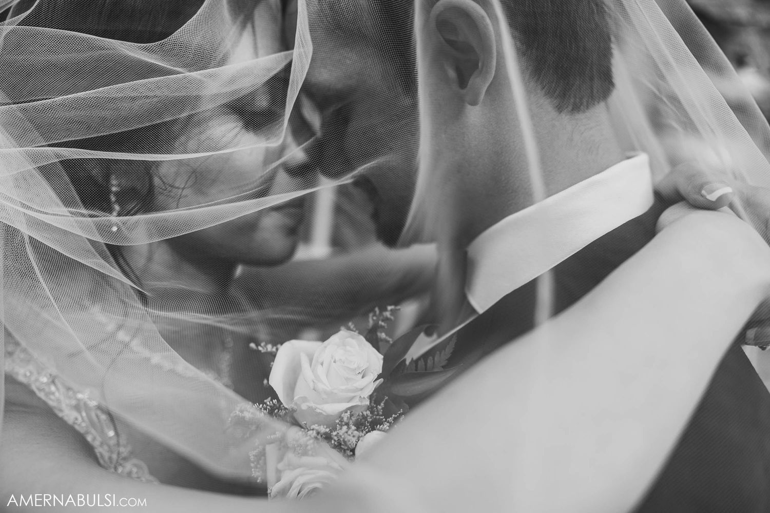 Black and white close-up shot of newlyweds sharing an intimate moment under a delicate veil.